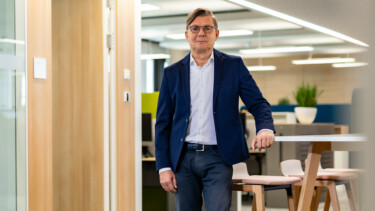 Jörg Staff steht an einem Bürotisch und blickt in die Kamera